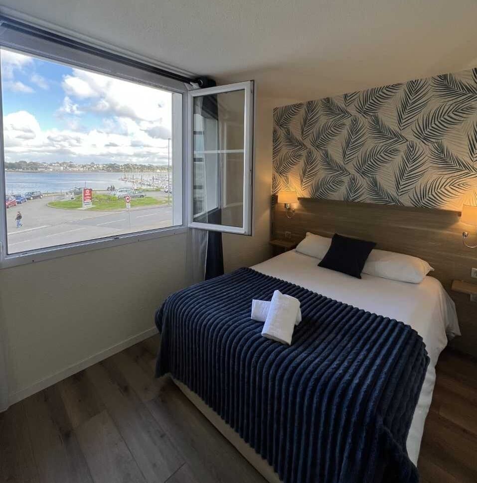 Hotel room with sea view and open window.