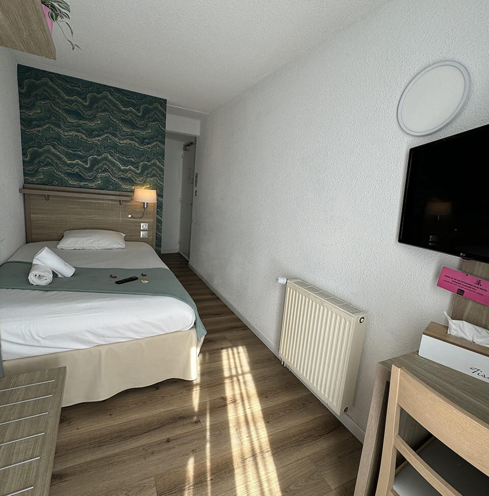 Small hotel room with single bed.