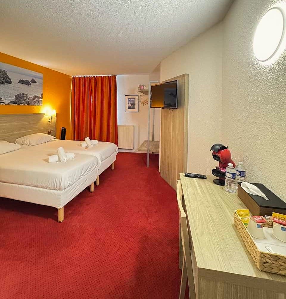 Hotel room with two beds and red carpet.