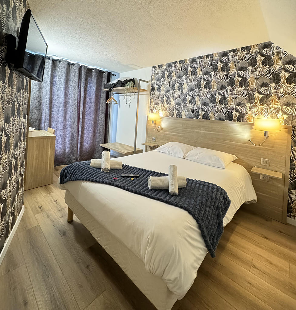 Cozy hotel room with double bed and wallpaper.