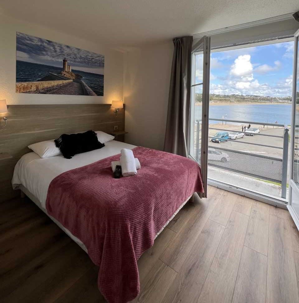 Hotel room with ocean view, bed, and balcony.