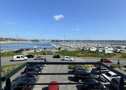 Vue sur parking et marina depuis un balcon.