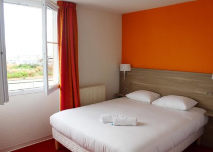 Chambre d'hôtel avec lit double et fenêtre ouverte.