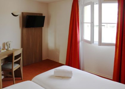 Chambre d'hôtel lumineuse avec lit et bureau